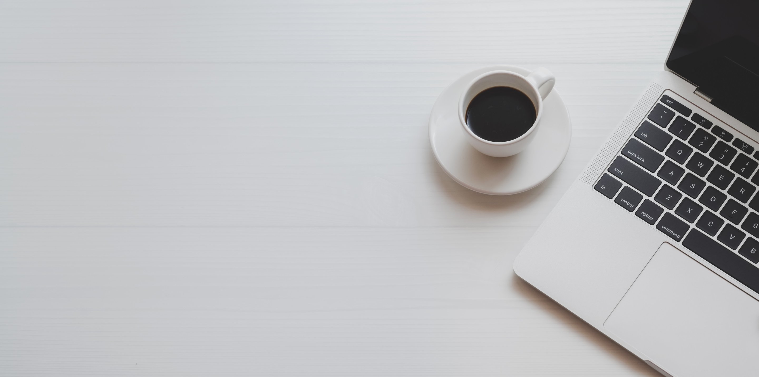 White Ceramic Cup on White Saucer Beside Laptop Computer 